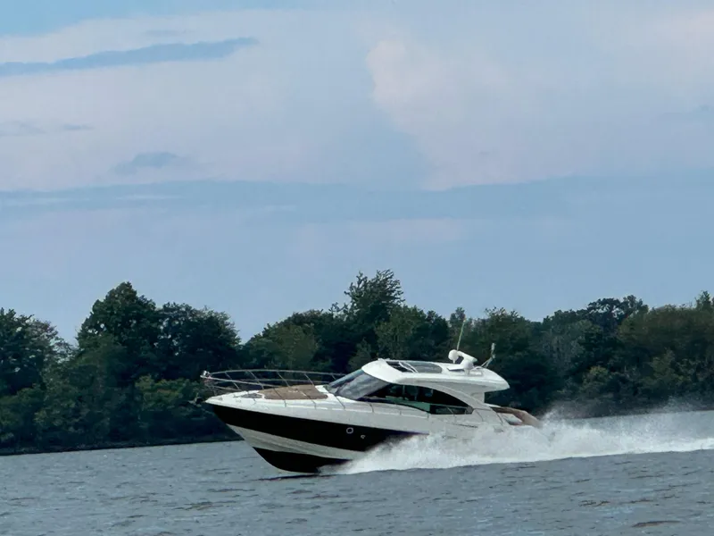 Slide: The Image of 2014 Cruisers Cantius yacht speeding on a lake with trees in the background. - 1