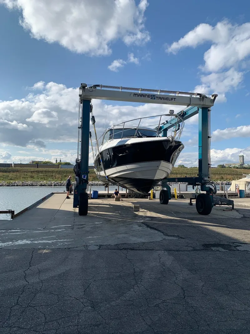 Slide: The Image of 2014 Cruisers Cantius yacht being lifted at a marina under a blue sky. - 4