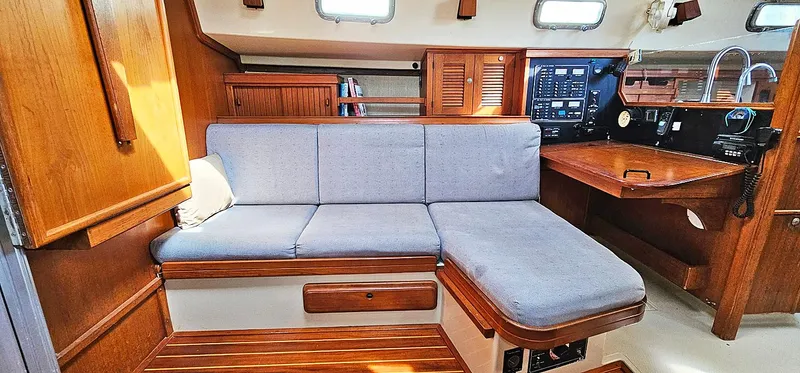 Slide: The Image of Interior of 1997 Island Packet 40 sailboat with wooden cabinetry and blue cushioned seating. - 4