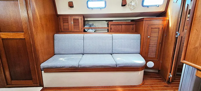 Slide: The Image of Interior of 1997 Island Packet 40 sailboat with wooden cabinetry and cushioned seating. - 5