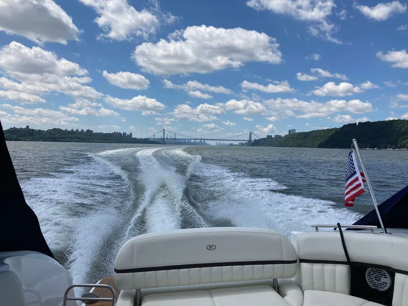 Slide: The Image of 2018 Cobalt R35 boat cruising on a river with scenic bridge and cloudy sky. - 25