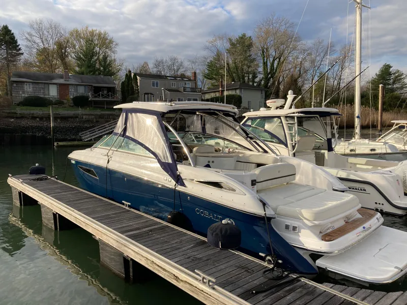 Slide: The Image of 2018 Cobalt R35 boat docked at marina, surrounded by trees and houses. - 3