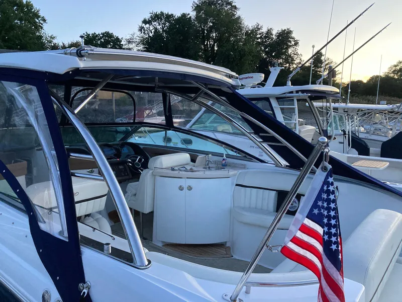 Slide: The Image of 2018 Cobalt R35 boat with American flag, docked at marina, surrounded by trees. - 5