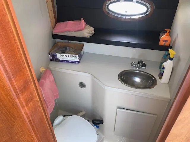 Slide: The Image of 1992 Carver 33 Aft Cabin bathroom with sink, toilet, and toiletries. - 11