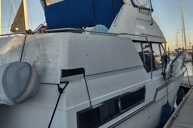 Slide: The Image of 1992 Carver 33 Aft Cabin yacht docked at marina, featuring blue canopy and white exterior. - 4