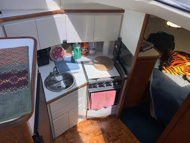 Slide: The Image of 1992 Carver 33 Aft Cabin kitchen with sink, stove, and cozy sleeping area. - 14