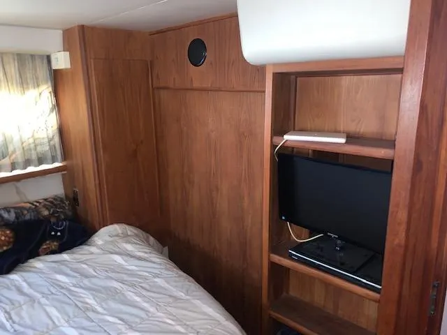 Slide: The Image of 1992 Carver 33 Aft Cabin interior with wood paneling, bed, and small TV shelf. - 20