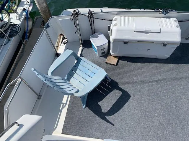 Slide: The Image of 1992 Carver 33 Aft Cabin deck with chair and cooler, docked by water. - 23