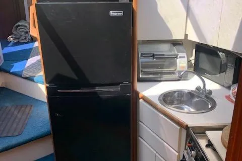 Slide: The Image of 1992 Carver 33 Aft Cabin kitchen with black fridge, sink, and appliances. - 34