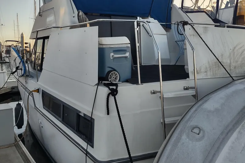 Slide: The Image of 1992 Carver 33 Aft Cabin boat docked, featuring a blue canopy and cooler on deck. - 38