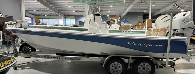 Slide: The Image of 2025 NauticStar 214 Bay boat on trailer in showroom, side view. - 0