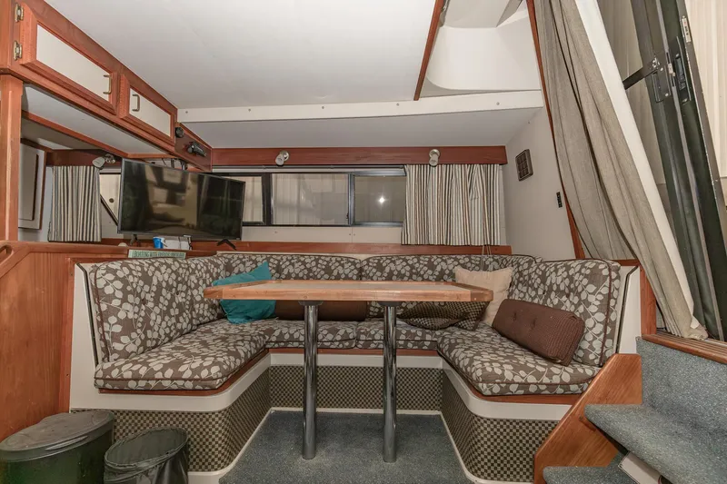 Slide: The Image of 1987 Carver 3697 Mariner interior with cozy dining area, patterned seating, and mounted TV. - 10