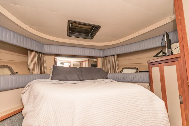 Slide: The Image of 1987 Carver 3697 Mariner cabin interior with bed, wood cabinetry, and portholes. - 24
