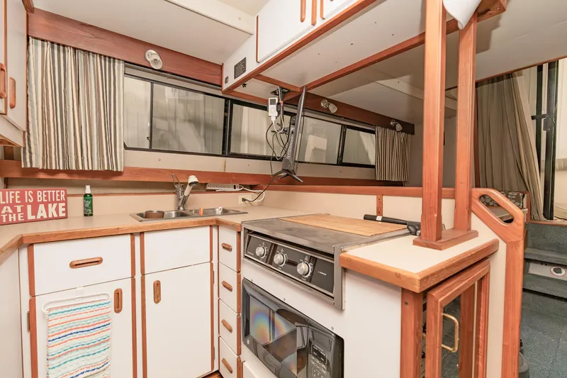 Slide: The Image of 1987 Carver 3697 Mariner kitchen with stove, sink, and striped curtains. - 14