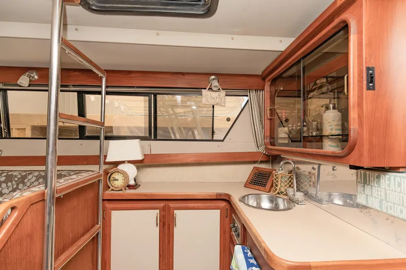 Slide: The Image of 1987 Carver 3697 Mariner yacht interior with wood cabinetry and compact kitchen area. - 17