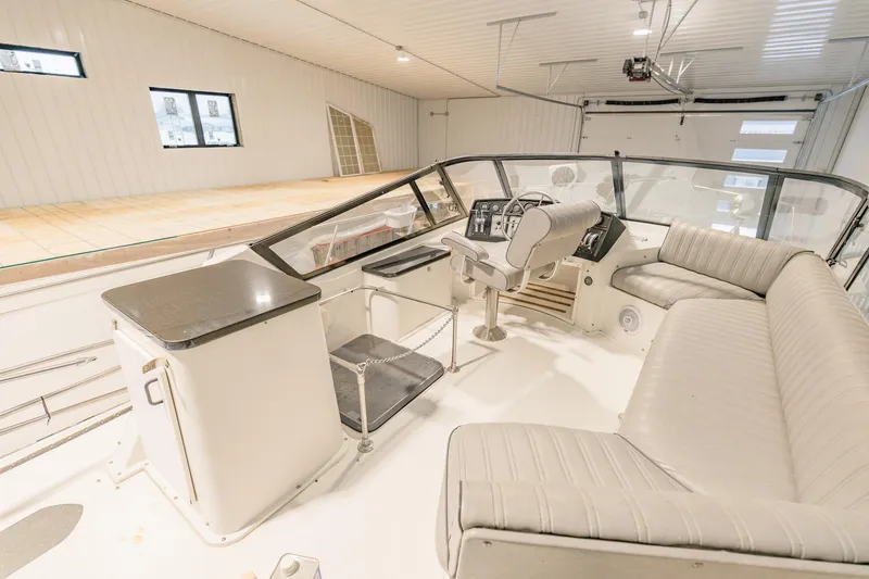 Slide: The Image of 1987 Carver 3697 Mariner boat interior with helm, seating, and controls in a spacious garage. - 36
