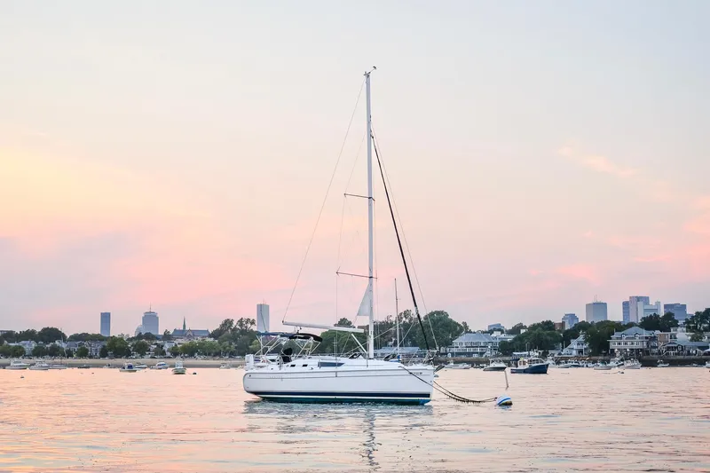 The Image of 2006 Hunter 31 sailboat anchored at sunset with city skyline in background. - 0