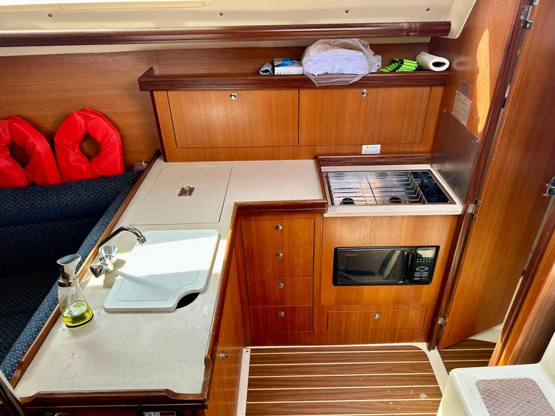 Slide: The Image of 2006 Hunter 31 yacht kitchen with sink, stove, and wooden cabinetry. - 31