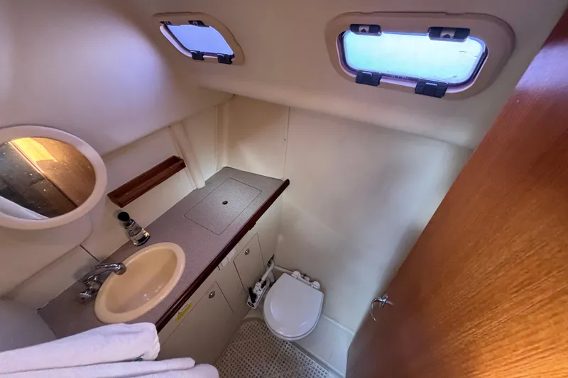 Slide: The Image of 2006 Hunter 31 yacht bathroom with sink, toilet, and portholes. - 57