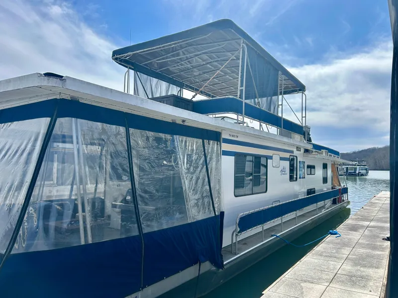 Slide: The Image of 1987 Jamestowner houseboat docked on a sunny day with blue canopy and clear windows. - 0