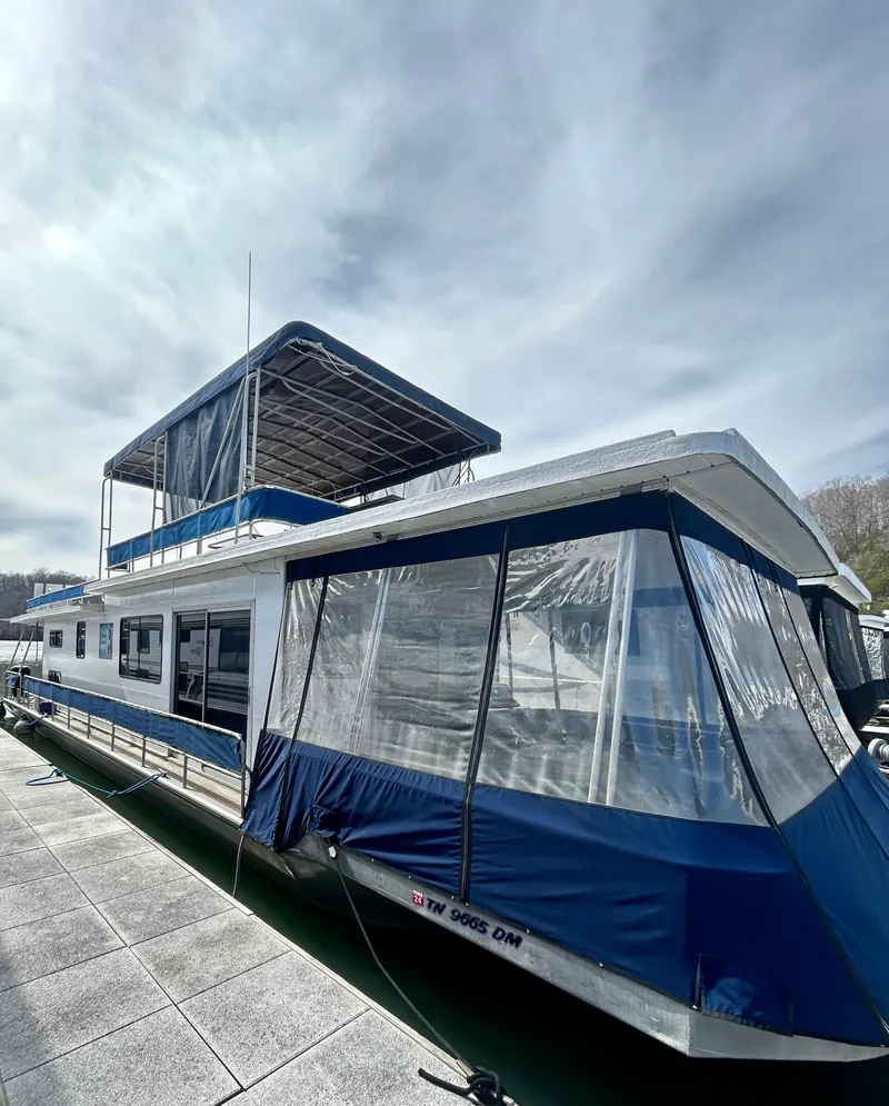 Slide: The Image of 1987 Jamestowner houseboat with blue accents docked under a cloudy sky. - 1