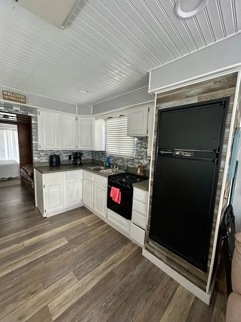 Slide: The Image of 1987 Jamestowner houseboat kitchen with white cabinets, modern appliances, and wood flooring. - 10