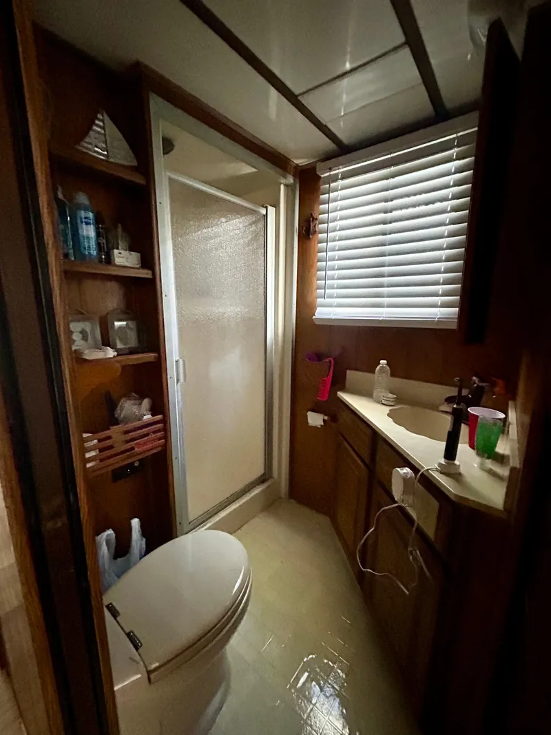 Slide: The Image of 1987 Jamestowner houseboat bathroom with shower, toilet, sink, and storage shelves. - 15