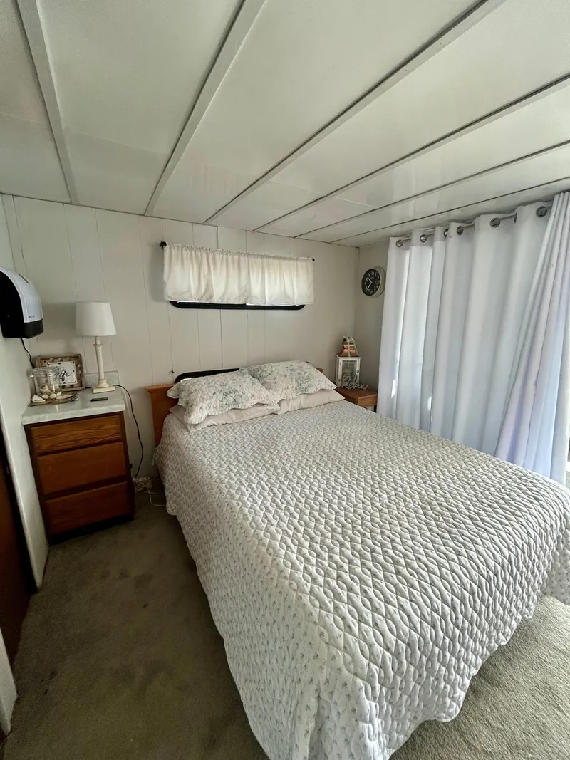 Slide: The Image of Cozy bedroom interior in a 1987 Jamestowner houseboat with white bedding and curtains. - 16