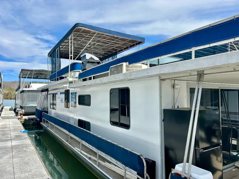 Slide: The Image of 1987 Jamestowner houseboat docked, featuring blue accents and upper deck under a clear sky. - 24