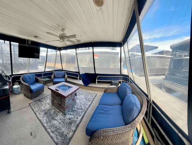 Slide: The Image of 1987 Jamestowner houseboat interior with blue cushioned seating, fire pit, and screened windows. - 4