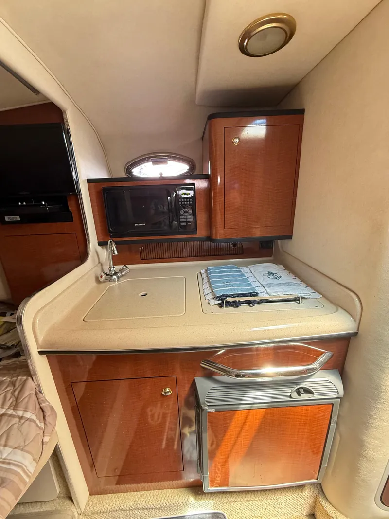 Slide: The Image of 2004 Sea Ray 280 Sundancer cabin kitchen with microwave, sink, and storage cabinets. - 11
