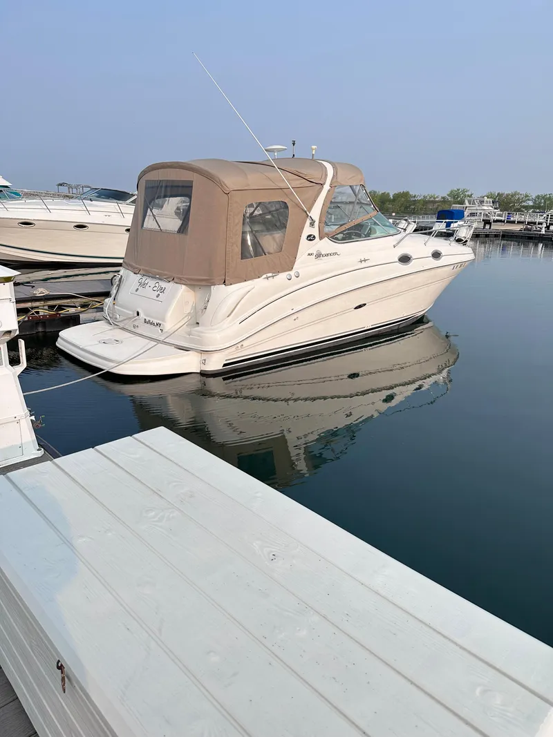Slide: The Image of 2004 Sea Ray 280 Sundancer boat docked in a marina, featuring a beige canopy. - 6