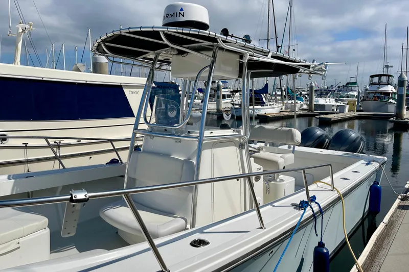 Slide: The Image of 2016 Parker 2501 Center Console boat docked at marina, featuring dual engines and T-top. - 8