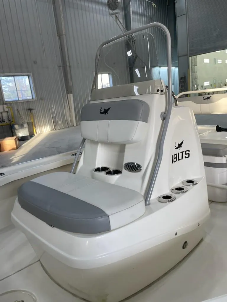 Slide: The Image of 2024 Mako 18 LTS boat interior with seating and console in a warehouse. - 5