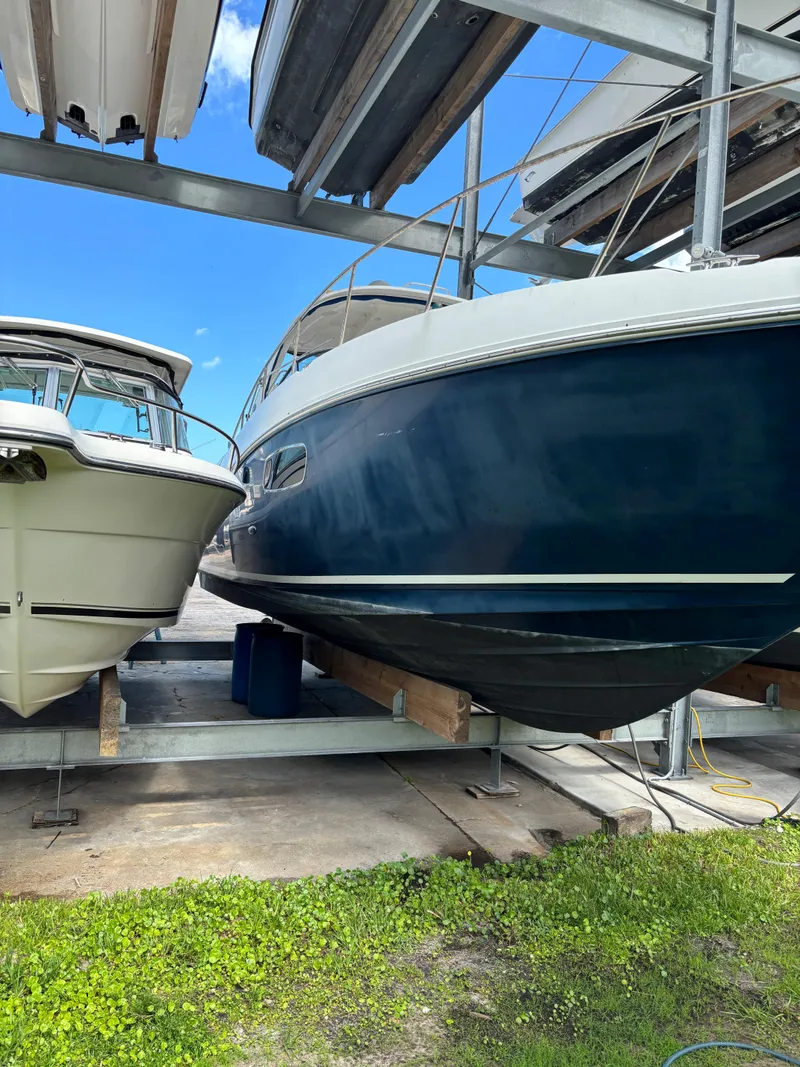 Slide: The Image of 2010 Sea Ray 38 boat stored on a rack beside another vessel, under a clear blue sky. - 0