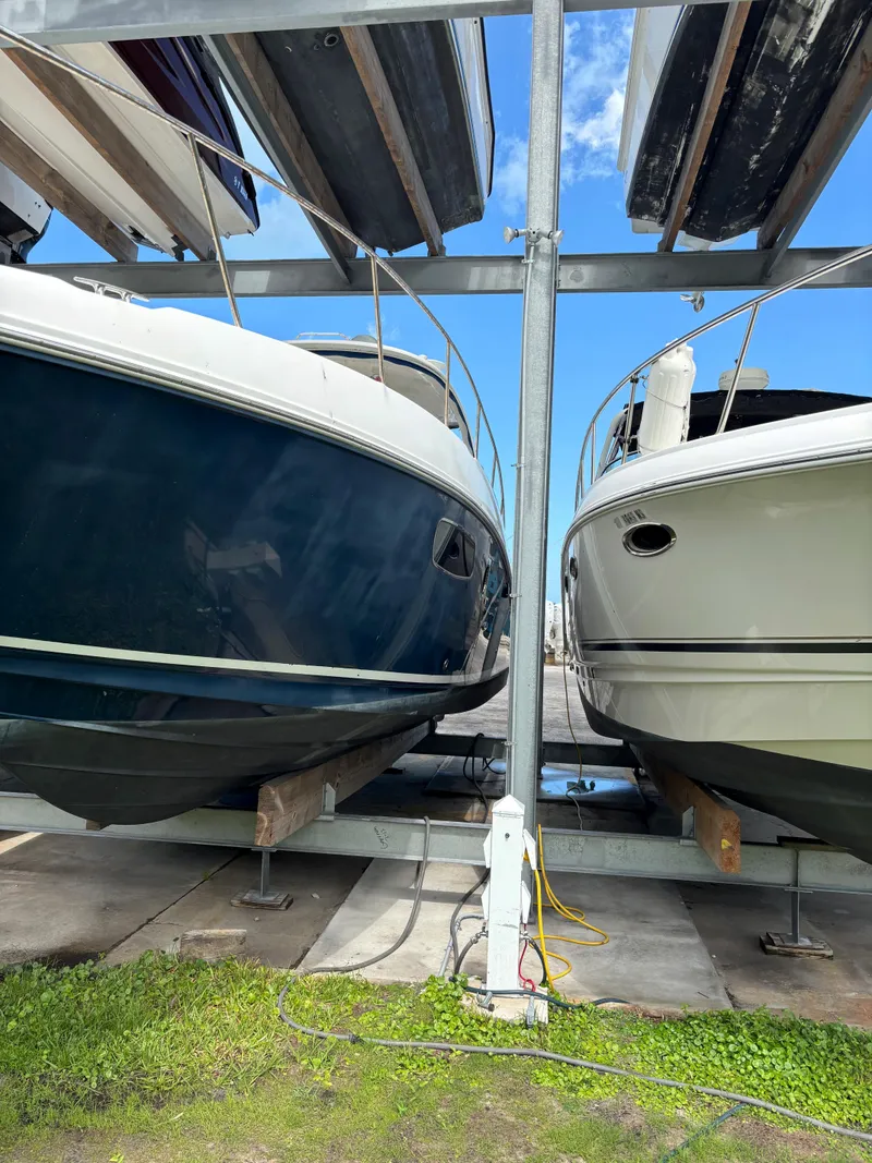 Slide: The Image of Two Sea Ray 38 boats from 2010 stored on racks under a clear blue sky. - 1