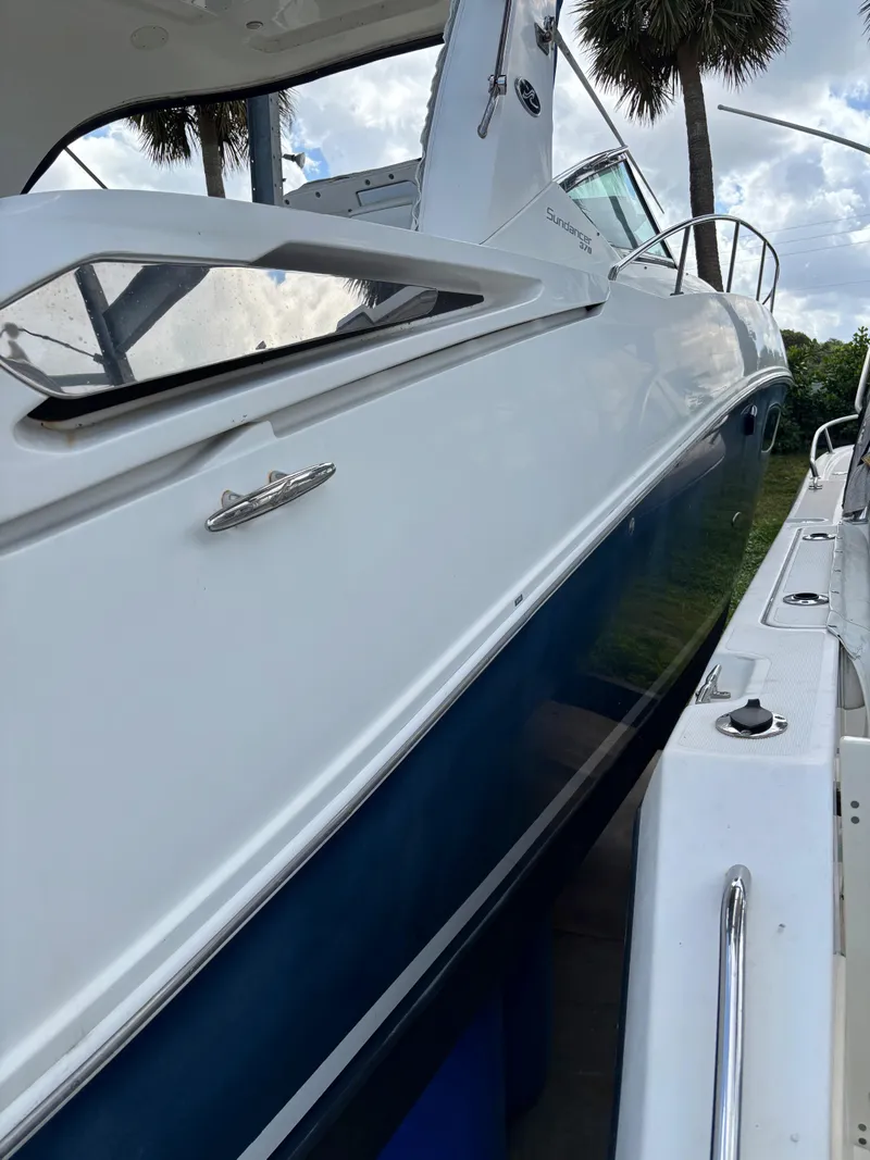 Slide: The Image of 2010 Sea Ray 38 boat, side view, docked with palm trees in background. - 2