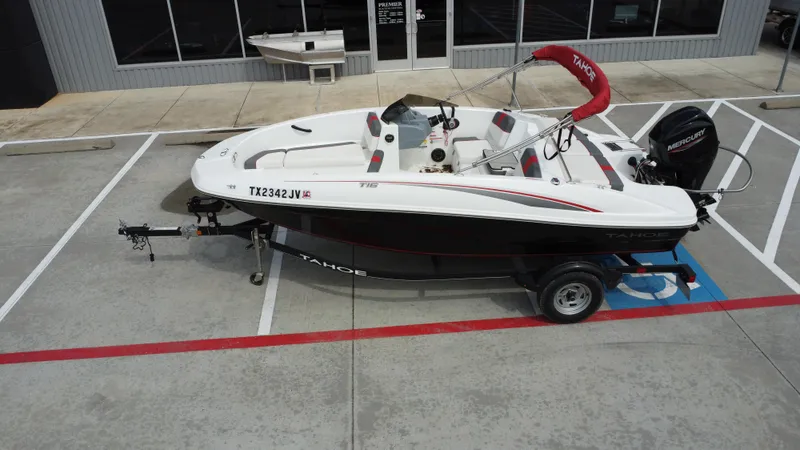 Slide: The Image of 2021 TAHOE TAHT16 boat on trailer, parked in a lot, featuring Mercury engine. - 16