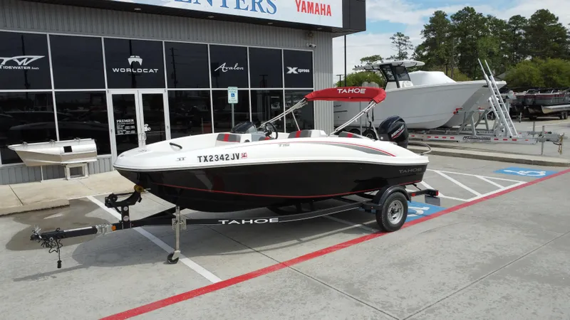 Slide: The Image of 2021 TAHOE TAHT16 boat on trailer outside dealership, featuring sleek black and white design. - 3
