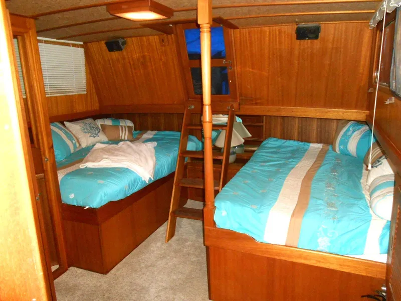 Slide: The Image of 1983 Californian 42 yacht cabin with twin beds, wooden interior, and blue bedding. - 12