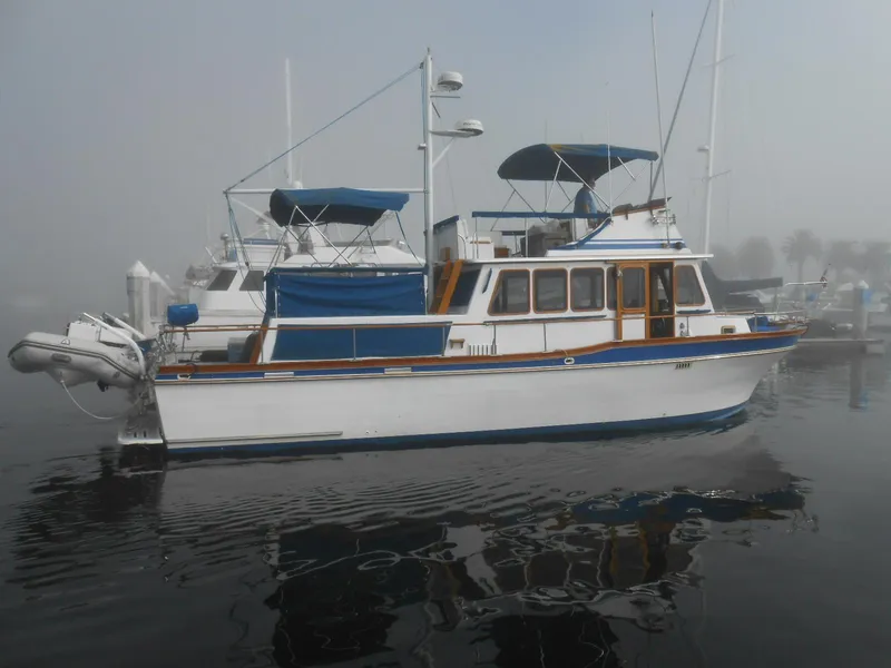 Slide: The Image of 1983 Californian 42 yacht with blue canopy, docked in a foggy marina. - 19