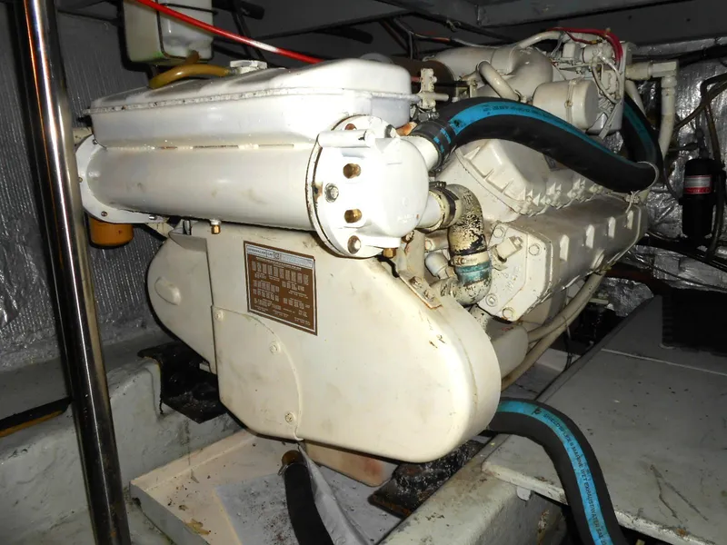 Slide: The Image of 1983 Californian 42 engine, white with blue hoses, in a boat's engine room. - 22