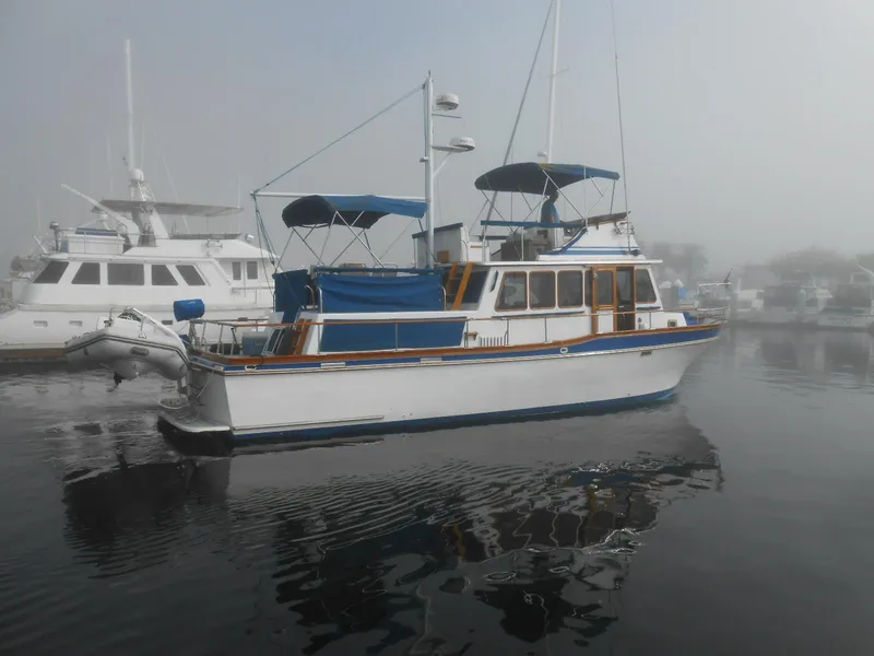 Slide: The Image of 1983 Californian 42 yacht docked in a foggy marina, featuring blue accents and multiple decks. - 24