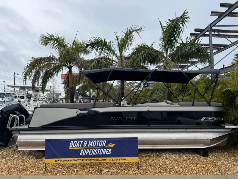 The Image of 2025 Avalon Catalina Quad Lounge boat displayed at dealership with palm trees in background. - 1
