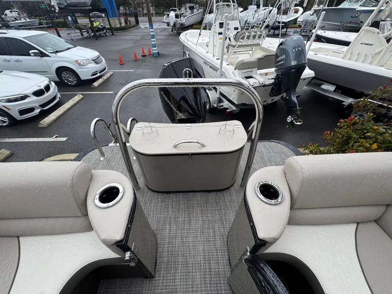 Slide: The Image of 2025 Avalon Catalina Quad Lounge boat interior with seating and cup holders in a marina setting. - 35