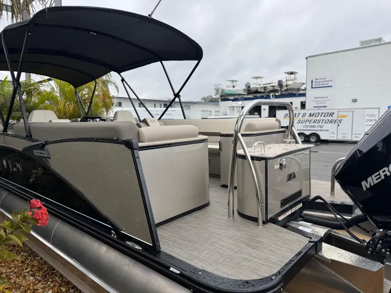 Slide: The Image of 2025 Avalon Catalina Quad Lounge boat with canopy, docked near a motor superstore. - 5