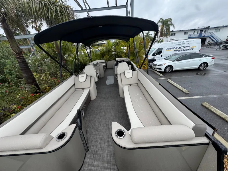Slide: The Image of 2025 Avalon Catalina Quad Lounge boat with spacious seating and canopy in a parking lot. - 8