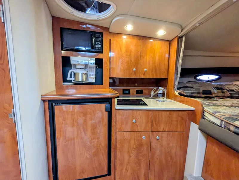 Slide: The Image of 2006 Cruisers Yachts 320 Express interior with kitchenette, featuring microwave, fridge, and sink. - 13