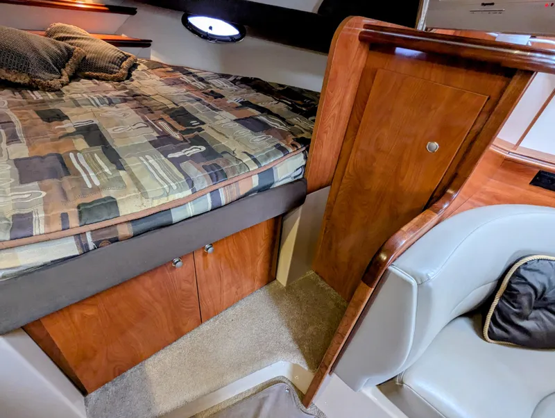 Slide: The Image of 2006 Cruisers Yachts 320 Express cabin interior with bed, wood paneling, and seating. - 17