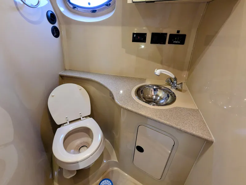 Slide: The Image of 2006 Cruisers Yachts 320 Express bathroom with toilet, sink, and porthole window. - 21
